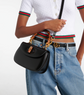 Person wearing a black Gucci handbag with a white background