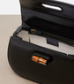 Black handbag with wooden handle on a beige surface