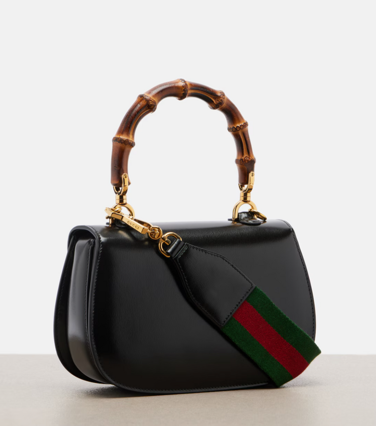Black handbag with bamboo handle and iconic green and red stripe on a light gray background