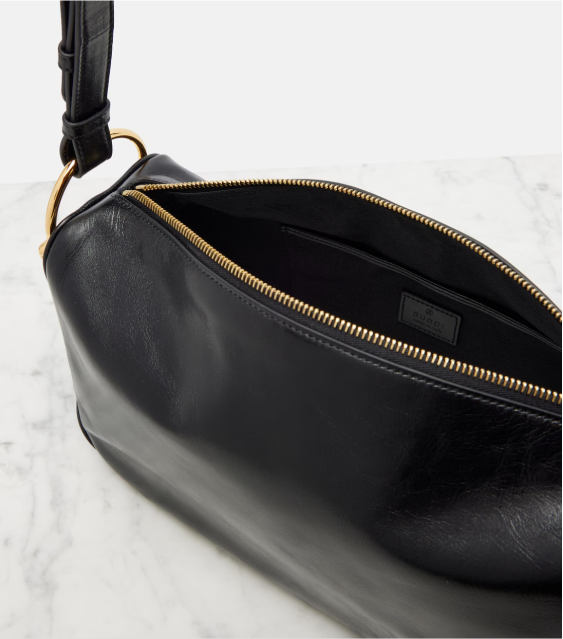 Black leather bag with gold zipper on a light gray background