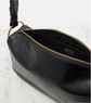Black leather bag with gold zipper on a light gray background